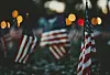 Flera amerikanska flaggor står tätt i skymningen med suddiga ljus i bakgrunden.