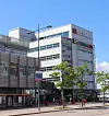 Flerplansbyggnad med butiksskyltar längs en tom stadsgata.
