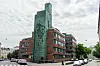 Folkpensionsanstaltens huvudbyggnad i Helsingfors vid en gata med bilar och molnig himmel.