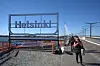 Helsinki-skylt vid en bro med en fotgängare på trottoaren.