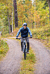 Sami Ylipihlaja cyklar på en grusväg genom en färgsprakande höstskog.