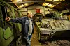 Besökare bredvid gröna pansarfordon i en militärhistorisk museihall.