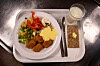 Bricka med skolmat, grönsaker, panerade bollar, bröd och ett glas mjölk.