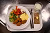 Bricka med skolmat, grönsaker, panerade bollar, bröd och ett glas mjölk.