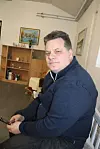 Peter Sjökvist sitter i ett rum med bokhylla och tavlor och ser mot kameran.
