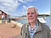Björn Rönnlöf står vid en småbåtshamn med vatten, bryggor och hus i bakgrunden.