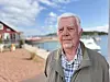 Björn Rönnlöf står vid en småbåtshamn med vatten, bryggor och hus i bakgrunden.