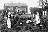 Människor arbetar på en potatisåker framför en gård i Alberga i Esbo 1918.